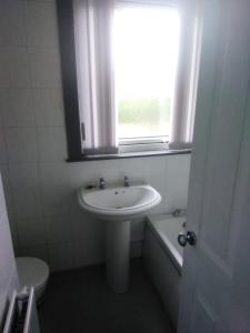 a bathroom with a sink and a toilet and a window at Alberto's in Broxburn