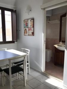 Il comprend une cuisine avec une table et des chaises ainsi qu'une salle de bains. dans l'établissement Appartamento La Cementina, à Trapani