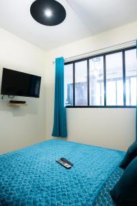 um quarto com uma televisão e um controlo remoto numa cama em Le Privilège appartement standing, piscine, terrasse, jardin, parking privé em Cayenne