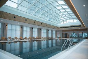 a swimming pool with chairs and a glass ceiling at Batumi Premiums Apartments Betta in Batumi