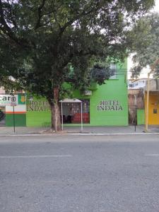 a building with a tree in front of a street at Hotel Indaiá in Governador Valadares