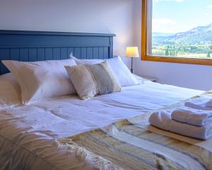 a bed with white sheets and pillows and a window at Oliver Mountain Home Cabin in San Martín de los Andes