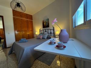 Un dormitorio con una cama y una mesa con un jarrón. en Sarah Kite II Vv, Room 1, en Playa del Burrero