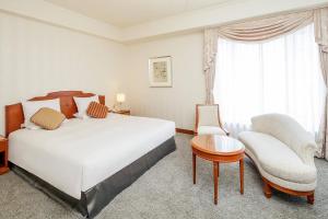 大阪市にあるKOKO HOTEL 大阪心斎橋の大きなベッドと椅子が備わるホテルルームです。