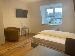 ein Schlafzimmer mit einem Bett, einem Stuhl und einem Fenster in der Unterkunft SCHNYDER'S HOME Studio_2 in Rapperswil-Jona