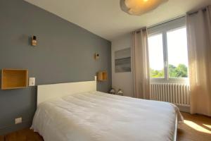 Un dormitorio con una gran cama blanca y una ventana en House with garden ideal D-DAY beaches and Caen en Hermanville-sur-Mer