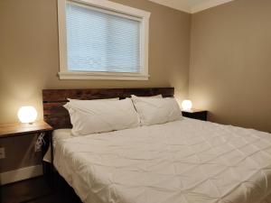 a bedroom with a large white bed with two lamps at Private Suite w King Bed, Ground Level, Naturally Bright in Vancouver