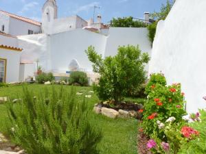 een tuin voor een wit huis met bloemen bij Páteo dos Oliveira - Casa da Cocheira in Évora