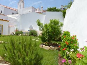 un giardino di fronte a una casa bianca con fiori di Páteo dos Oliveira - Casa da Cocheira a Évora