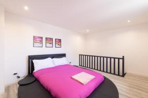 a bedroom with a black bed with a pink blanket at Glm Residences 1 in Saint-Quentin