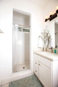 a white bathroom with a shower and a sink at Mid Century Modern - Walk to Dodger Stadium, DTLA in Los Angeles