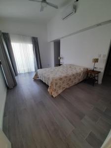 1 dormitorio blanco con 1 cama y suelo de madera en PALAZZOLO CASA DE CAMPO Y RELAX en San Pedro