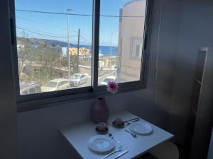 Sarah Kite II Vv, Room 2 في Playa del Burrero: طاولة مع صحون و مزهرية مع وردة على النافذة