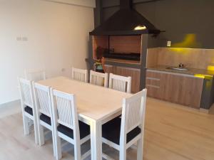a kitchen with a wooden table and white chairs at DFC Salta Estudio 2p in Salta