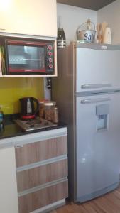 a small kitchen with a microwave and a refrigerator at DFC Salta Estudio 2p in Salta