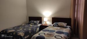 - une chambre avec deux lits et une lampe sur une table dans l'établissement Departamento El-Shaddai, à Tarija