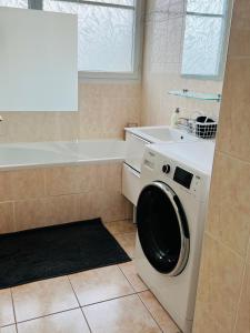 a white washing machine in a bathroom with a tub at Superbe Appartement lumineux proche Disney in Montévrain