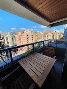 a wooden bench on a balcony with a view of a city at LOCADOR Nueva Cordoba 10A in Cordoba