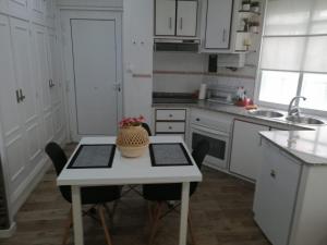 una cocina con armarios blancos y una mesa con sillas. en Estudio - Casco histórico de Cedeira en Cedeira