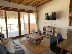 ein Wohnzimmer mit einem Sofa, einem Tisch und einem TV in der Unterkunft Casas Lua & Mar - Vichayito - Máncora in Vichayito