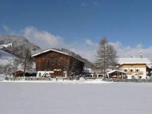 eine Scheune mit Schnee auf dem Boden vor einem Feld in der Unterkunft Obersinnlehenhof in Maishofen