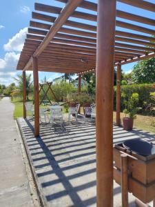 eine hölzerne Pergola mit Stühlen und Tischen auf einer Terrasse in der Unterkunft Casa com 3 quartos em Condomínio de Luxo in Gravatá