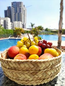 uma cesta de frutas sobre uma mesa perto de uma piscina em Luxury Stay em Sheikh Zayed
