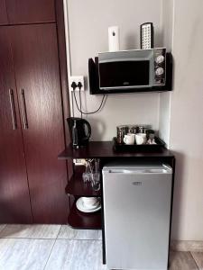 eine kleine Küche mit einer Mikrowelle und einem kleinen Kühlschrank in der Unterkunft Silken Trap Accommodation NO LOADSHEDDING in Johannesburg