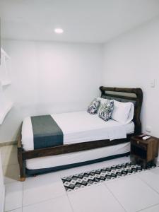 a bed in a room with a white wall at Hotel Tranvia in Santa Marta +10 photos