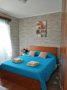 a bedroom with a blue bed with a brick wall at Casa Dos Mosteiros in Mosteiros