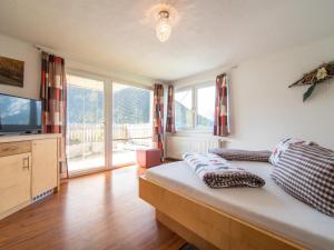 a bedroom with a bed and a tv andwindows at Haus Hauser in Tobadill