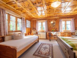 two beds in a room with wooden walls and windows at Landhaus Barbara in Silbertal