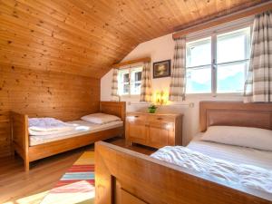two beds in a room with wooden walls at Sonnrasthütte in Untergaimberg