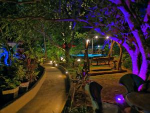 un jardín iluminado por la noche con luces púrpuras en Levona Garden Resort en Habarana