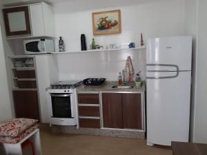 cocina con nevera blanca y fogones en Apartamento Ilha dos Patos Ingleses na Beira do Mar, en Florianópolis