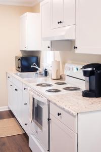 una cucina con armadi bianchi e un piano cottura bianco con forno di Adorable 2-bedroom bungalow near Easton, Denton a Denton