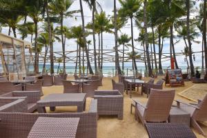 a beach with chairs and tables and palm trees at Ambassador In Paradise in Boracay