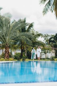 a man and a woman standing on the edge of a swimming pool at SS Villa & Resort in Trâpeăng