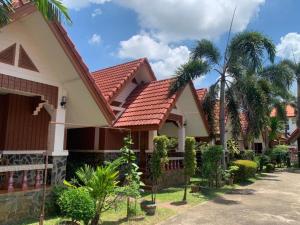 a house with a red roof and palm trees at Bunraksa Resort in Kamphaeng Phet