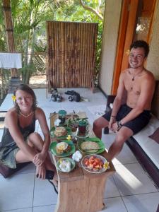 a man and a woman sitting at a table with food at Yuda Menjangan Homestay in Banyuwedang