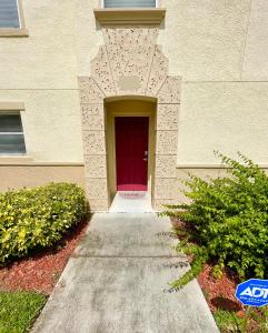 un edificio con una puerta roja y una acera en Cozy Oasis near Disney! 4 bedroom 3 bath Townhouse!, en Kissimmee