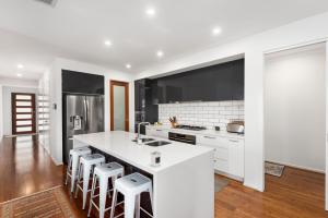 a kitchen with a white counter and stools at Beach Life in Indented Head