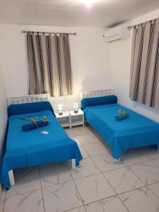 Dos camas en una habitación con sábanas azules. en Maison Indép, Spa, Mer, Jardin, Bien-être, en Les Trois-Îlets