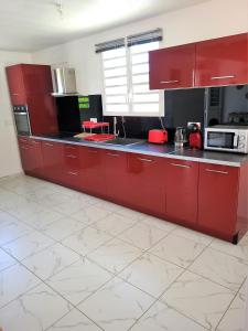 a kitchen with red cabinets and a counter top at Maison Indép, Spa, Mer, Jardin, Bien-être in Les Trois-Îlets