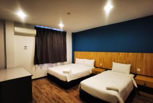 a hotel room with two beds and a blue wall at 3-Plus Hotel in Kota Kinabalu