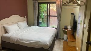 a bedroom with a white bed and a window at 小古堡民宿 The Little Castle - 完成訂房後務必要與屋主聯絡確認 in Tainan