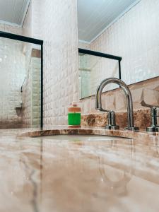 a bathroom with a sink and two faucets at Recanto do Loriano in Monte Verde