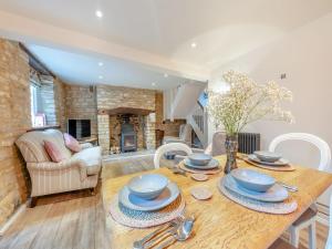 uma cozinha e sala de estar com uma mesa de madeira e cadeiras em Patience Cottage em Idbury