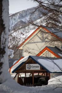 a sign in front of a snow covered building at Canopy Lodge - Boutique Lodge at Hakuba Cortina in Otari