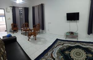 a living room with a couch and a table and a tv at Homestay D'Mama Īfor mūslimĪ in Tanjung Malim